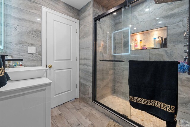 bathroom featuring hardwood / wood-style floors, sink, tile walls, and walk in shower