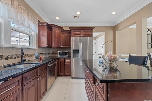 kitchen with crown molding, sink, stainless steel appliances, and a center island with sink