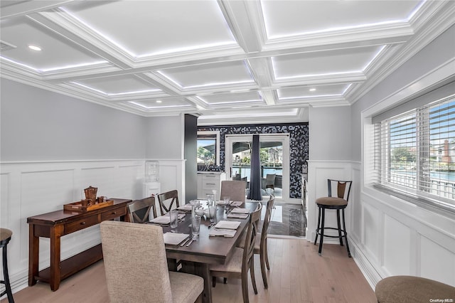 dining room featuring ornamental molding, light wood-type flooring, a healthy amount of sunlight, and coffered ceiling