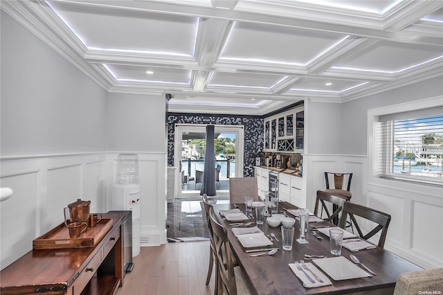 dining space with crown molding, a healthy amount of sunlight, coffered ceiling, and hardwood / wood-style flooring