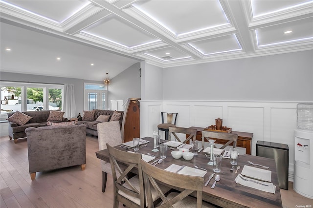 dining room with beamed ceiling, coffered ceiling, crown molding, and light hardwood / wood-style flooring