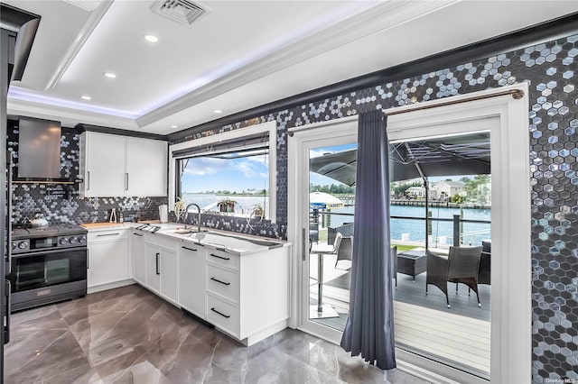 kitchen with tasteful backsplash, a water view, stainless steel electric stove, white cabinets, and ornamental molding