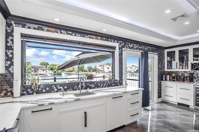 kitchen with white cabinets, a healthy amount of sunlight, a water view, and light stone counters