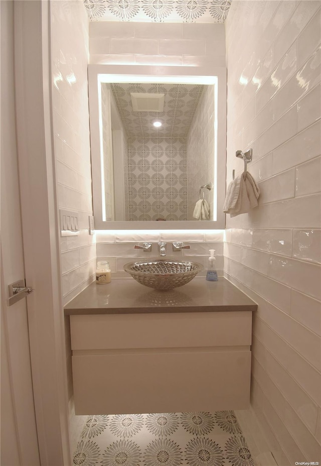 bathroom with tile patterned flooring, vanity, and tile walls