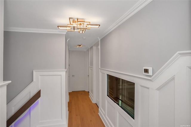 hall featuring light hardwood / wood-style floors, crown molding, and a notable chandelier