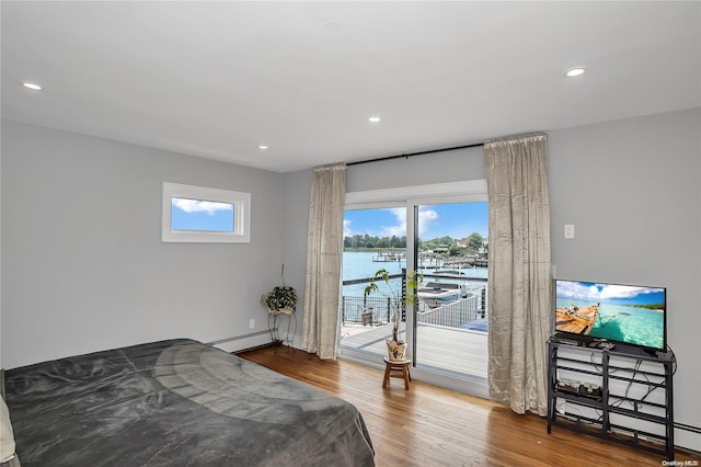 bedroom with hardwood / wood-style flooring, access to exterior, and baseboard heating