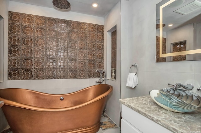 bathroom with vanity, a tub to relax in, and tile walls