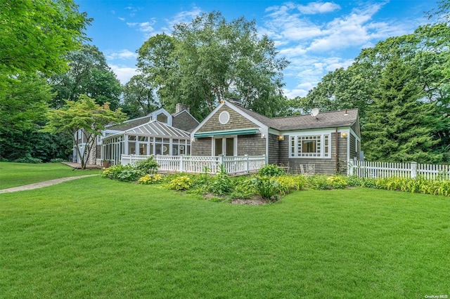 rear view of house featuring a sunroom, a yard, and a deck