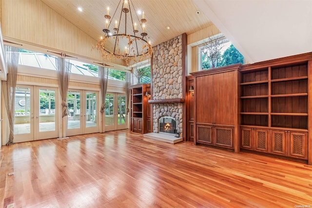 unfurnished living room with a fireplace, french doors, high vaulted ceiling, and light wood-type flooring