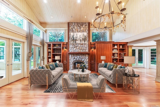 living room featuring a fireplace, french doors, high vaulted ceiling, and light hardwood / wood-style flooring