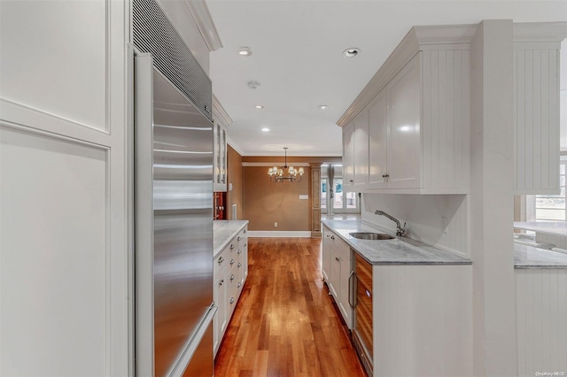 kitchen with light stone counters, plenty of natural light, built in fridge, and sink