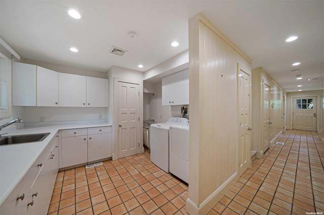 kitchen featuring washing machine and clothes dryer, white cabinetry, sink, and light tile patterned floors