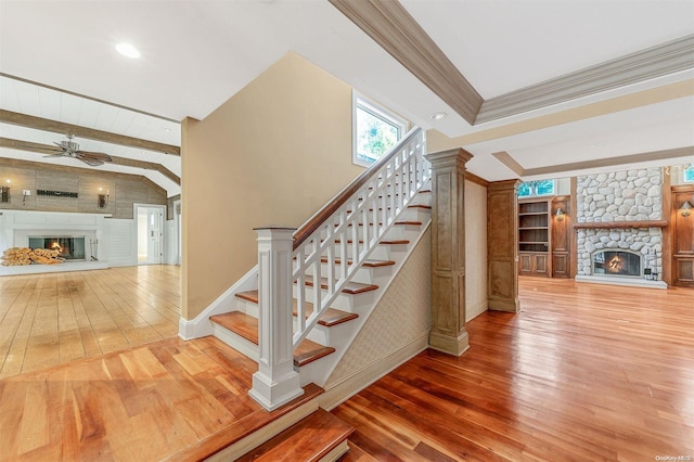 stairway featuring beam ceiling, ceiling fan, wood-type flooring, a fireplace, and ornamental molding