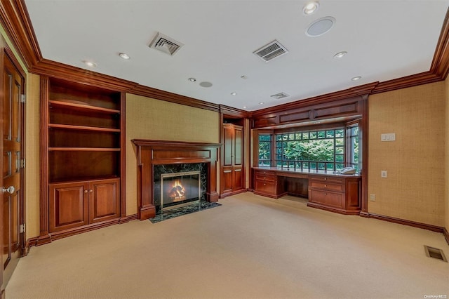 unfurnished living room featuring built in features, a high end fireplace, crown molding, light colored carpet, and built in desk