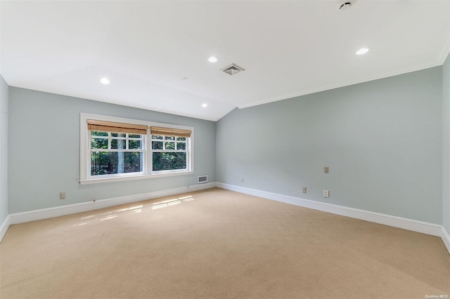 carpeted empty room with crown molding and vaulted ceiling