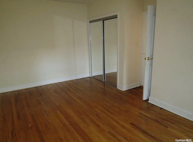 unfurnished bedroom with dark wood-type flooring and a closet