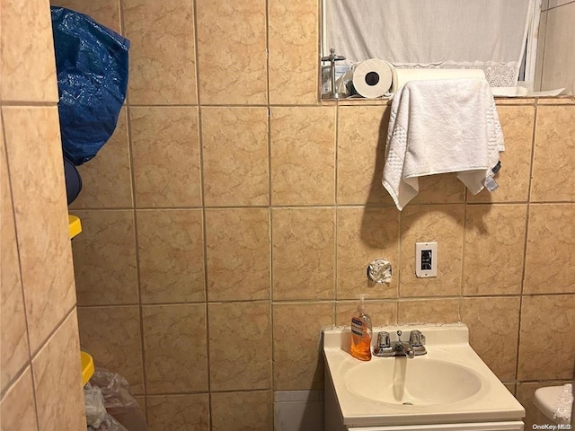 bathroom featuring vanity, toilet, and tile walls