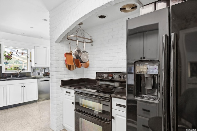 kitchen featuring white cabinets, sink, brick wall, and black appliances