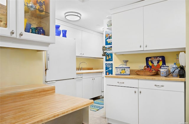 kitchen featuring white refrigerator, white cabinetry, and sink