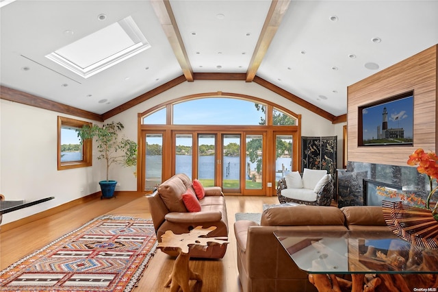 living room with wood-type flooring, a premium fireplace, french doors, and vaulted ceiling with skylight