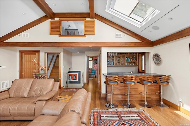 living room featuring beamed ceiling, hardwood / wood-style flooring, high vaulted ceiling, and bar