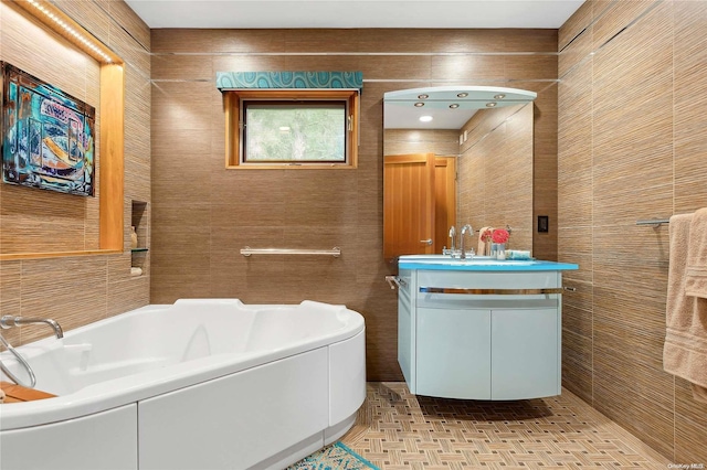 bathroom featuring a tub to relax in, vanity, and tile walls