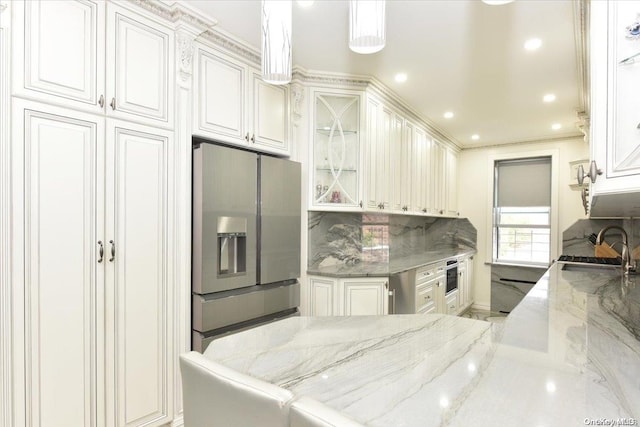 kitchen with pendant lighting, white cabinets, sink, light stone countertops, and appliances with stainless steel finishes