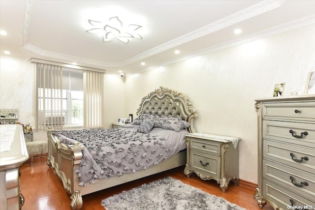 bedroom featuring a raised ceiling, crown molding, and dark hardwood / wood-style flooring