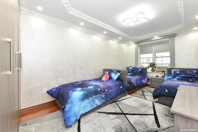 bedroom featuring light wood-type flooring, a raised ceiling, and ornamental molding