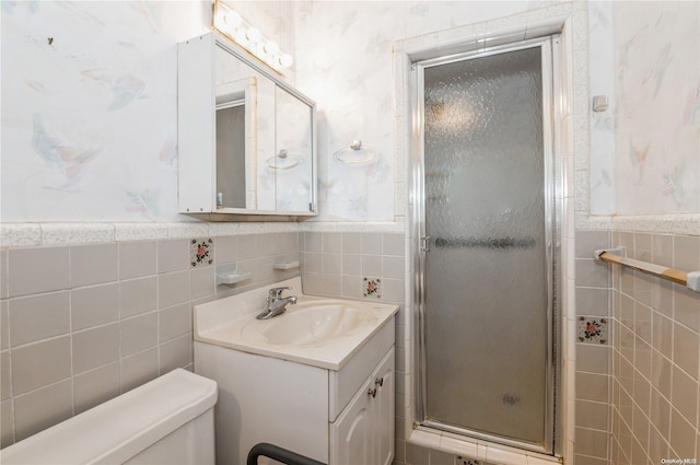 bathroom with vanity, a shower with shower door, tile walls, and toilet