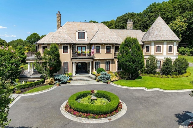 view of front facade featuring a balcony and a front lawn