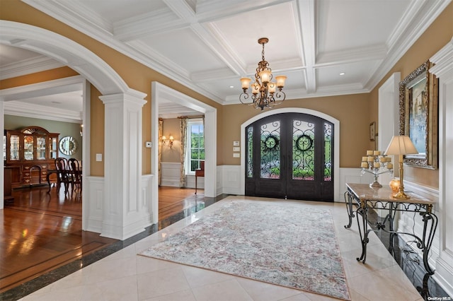 tiled foyer entrance with french doors, ornate columns, coffered ceiling, crown molding, and beam ceiling