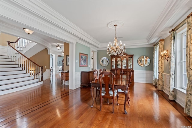 dining area featuring ornamental molding, hardwood / wood-style flooring, decorative columns, and a healthy amount of sunlight