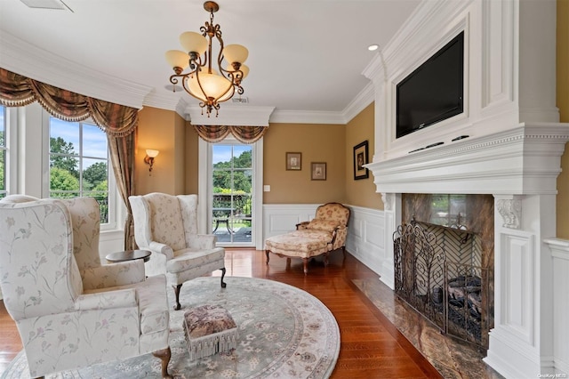 living area with a healthy amount of sunlight, ornamental molding, dark wood-type flooring, and an inviting chandelier