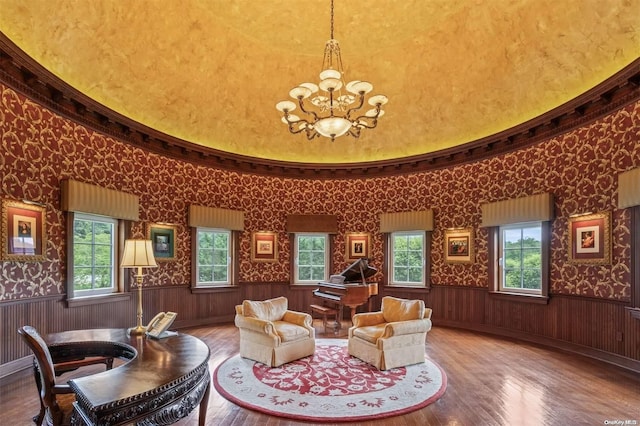 sitting room featuring a chandelier, a high ceiling, hardwood / wood-style flooring, and wooden walls