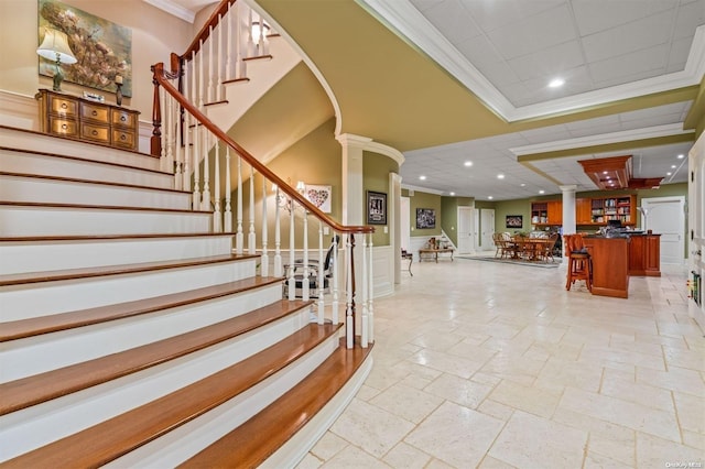 stairway featuring crown molding and decorative columns