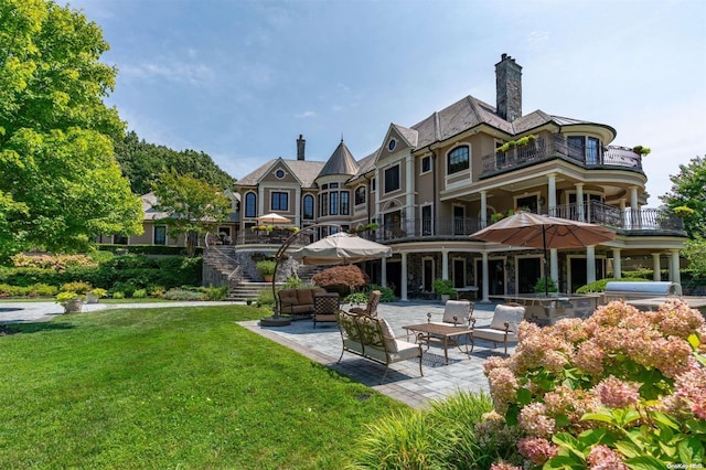 back of property featuring a lawn, an outdoor living space, a patio area, and a balcony