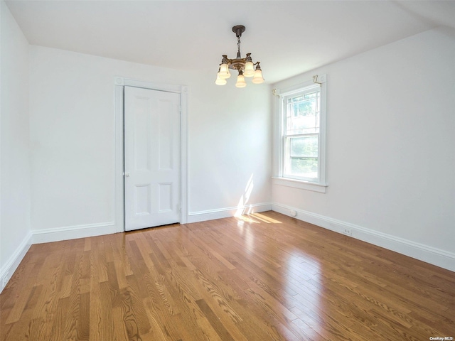 spare room featuring hardwood / wood-style flooring and an inviting chandelier