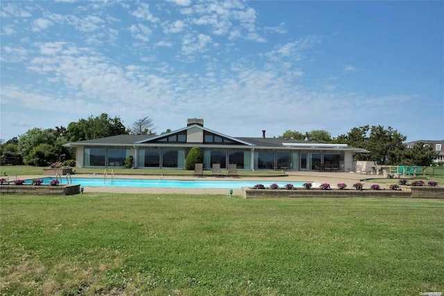 back of house with an outdoor pool and a lawn