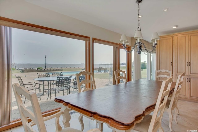 dining area with light tile patterned floors, a water view, and an inviting chandelier