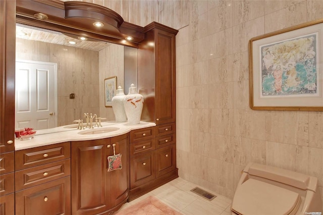 bathroom with tile patterned flooring, vanity, toilet, and tile walls