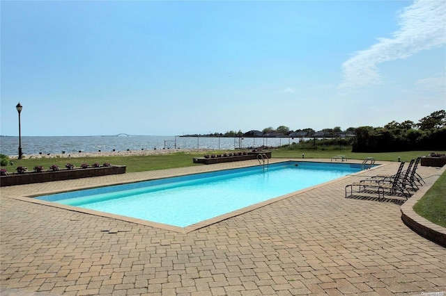 view of swimming pool featuring a water view and a patio