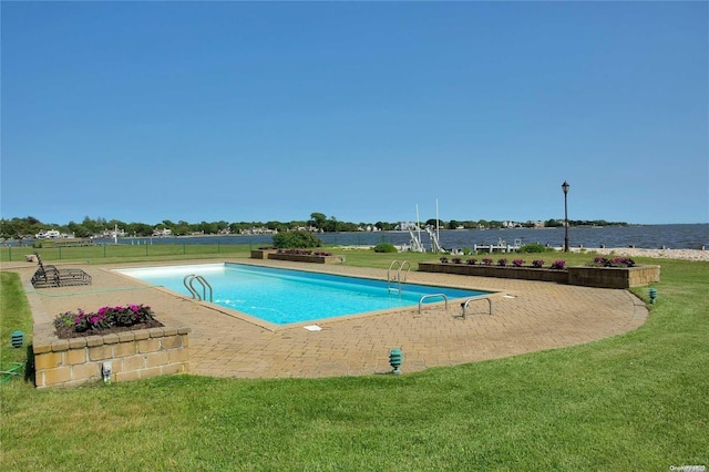 view of swimming pool featuring a yard, a water view, and a patio