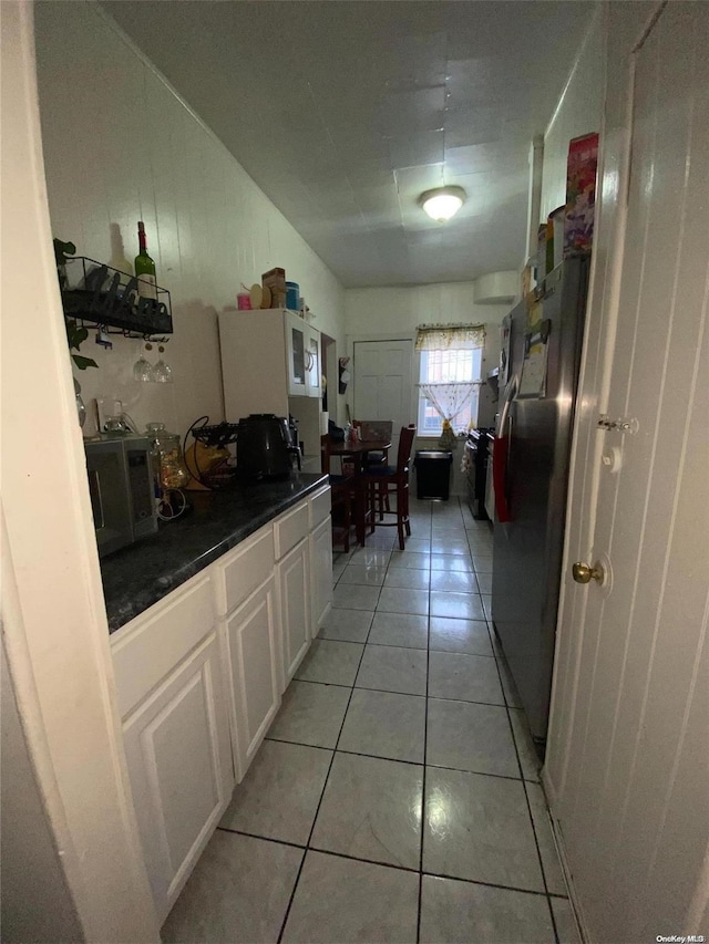 kitchen with white cabinets, light tile patterned floors, and stainless steel refrigerator