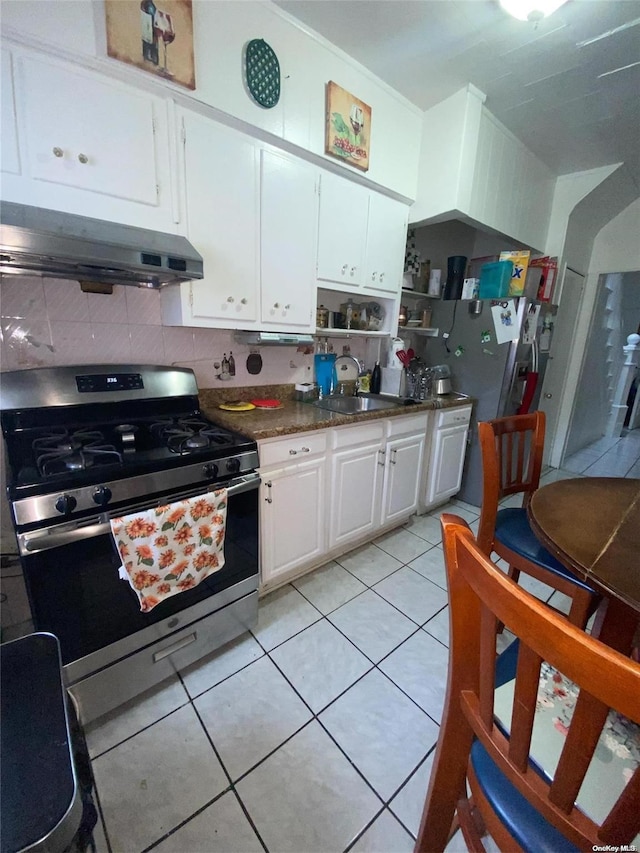 kitchen with light tile patterned flooring, sink, tasteful backsplash, gas stove, and white cabinetry