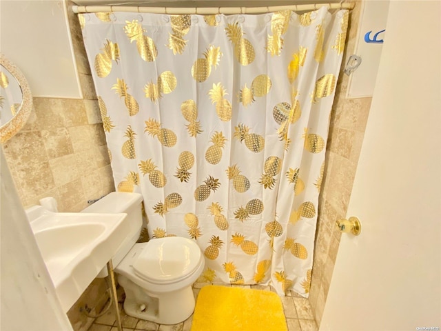 bathroom with tile patterned flooring, sink, toilet, and tile walls