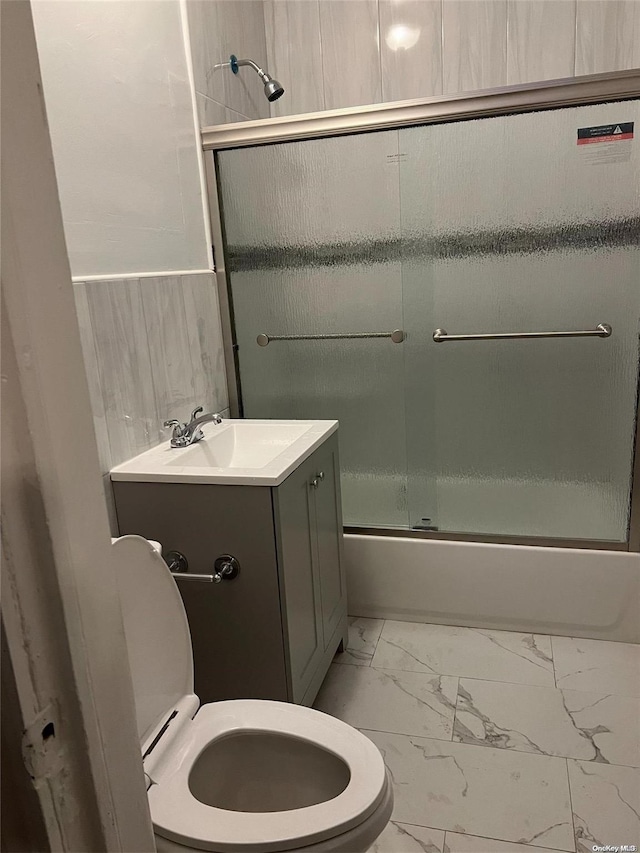 full bathroom featuring vanity, toilet, and shower / bath combination with glass door