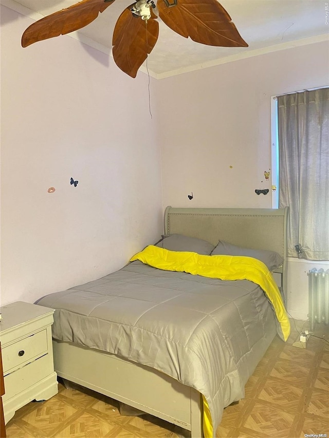 bedroom featuring ceiling fan, ornamental molding, radiator heating unit, and light parquet flooring