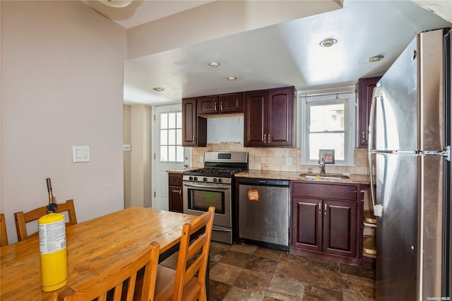 kitchen with light stone countertops, decorative backsplash, sink, and stainless steel appliances