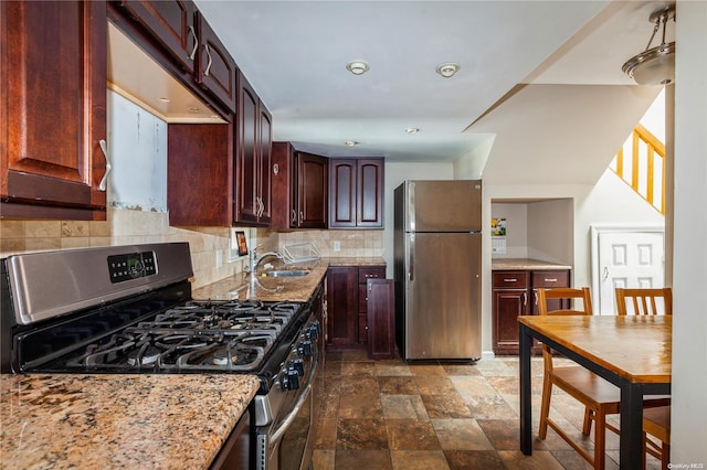 kitchen featuring tasteful backsplash, light stone counters, sink, and appliances with stainless steel finishes